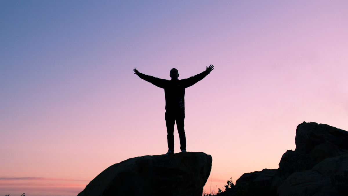 Man standing against sky with arms aloft