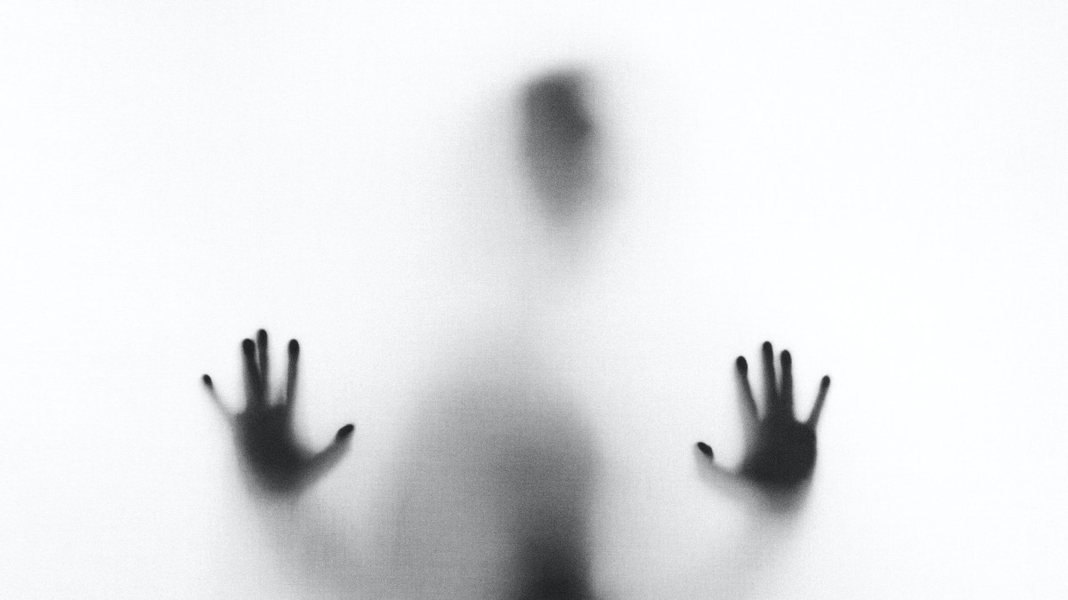 Blurry image of person with hands pressing against a glass screen